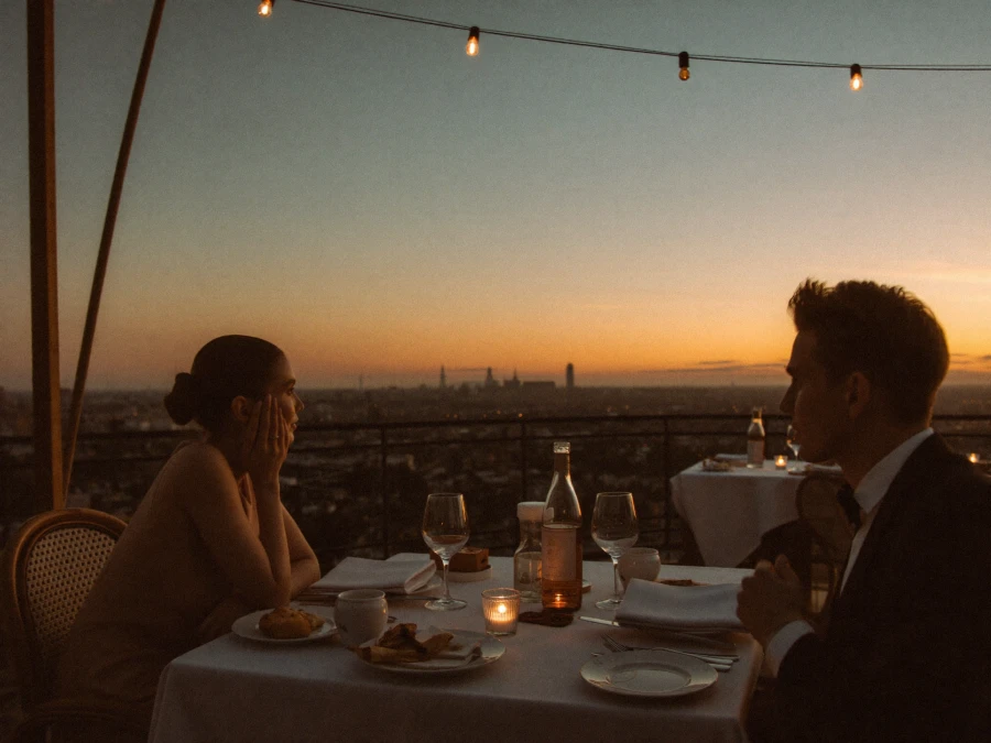 A romantic rooftop terrace dinner at sunset with a city view.