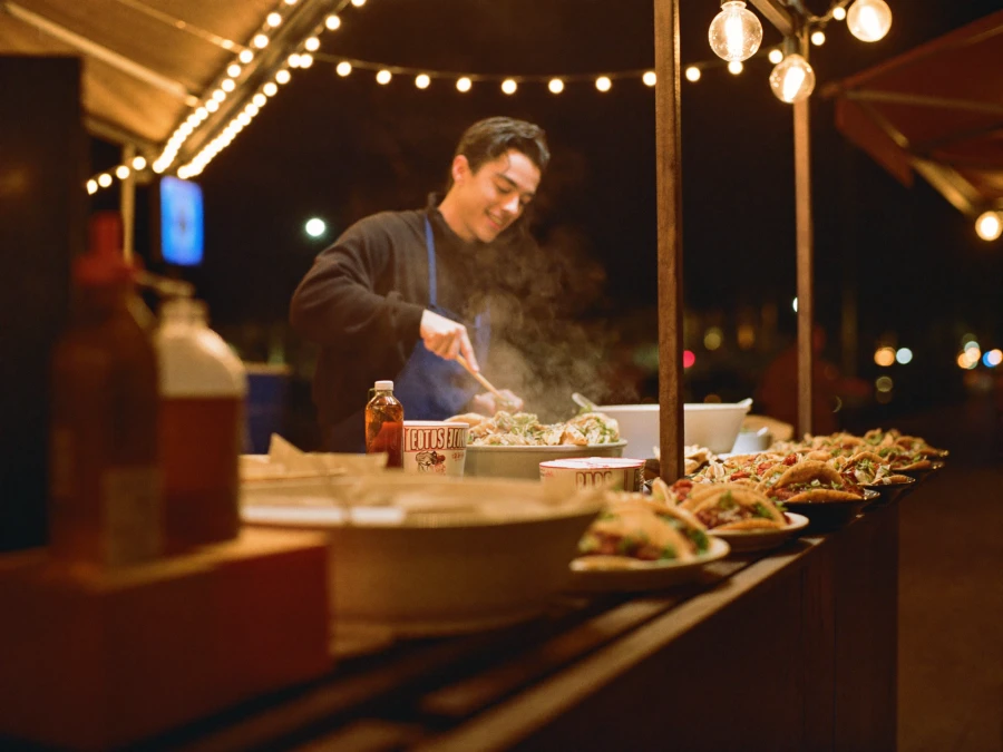 A taco stand at a lively night market, tacos being served.